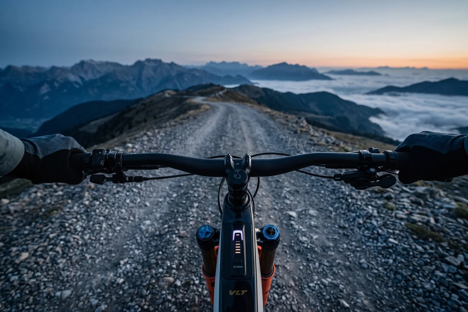 Norco Range VLT CX C1, rider's view over the cockpit descending a mountain fire road at dusk